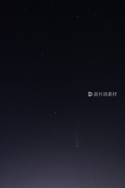 Comet Neowise in the starry night sky. Vertical frame with a green comet.